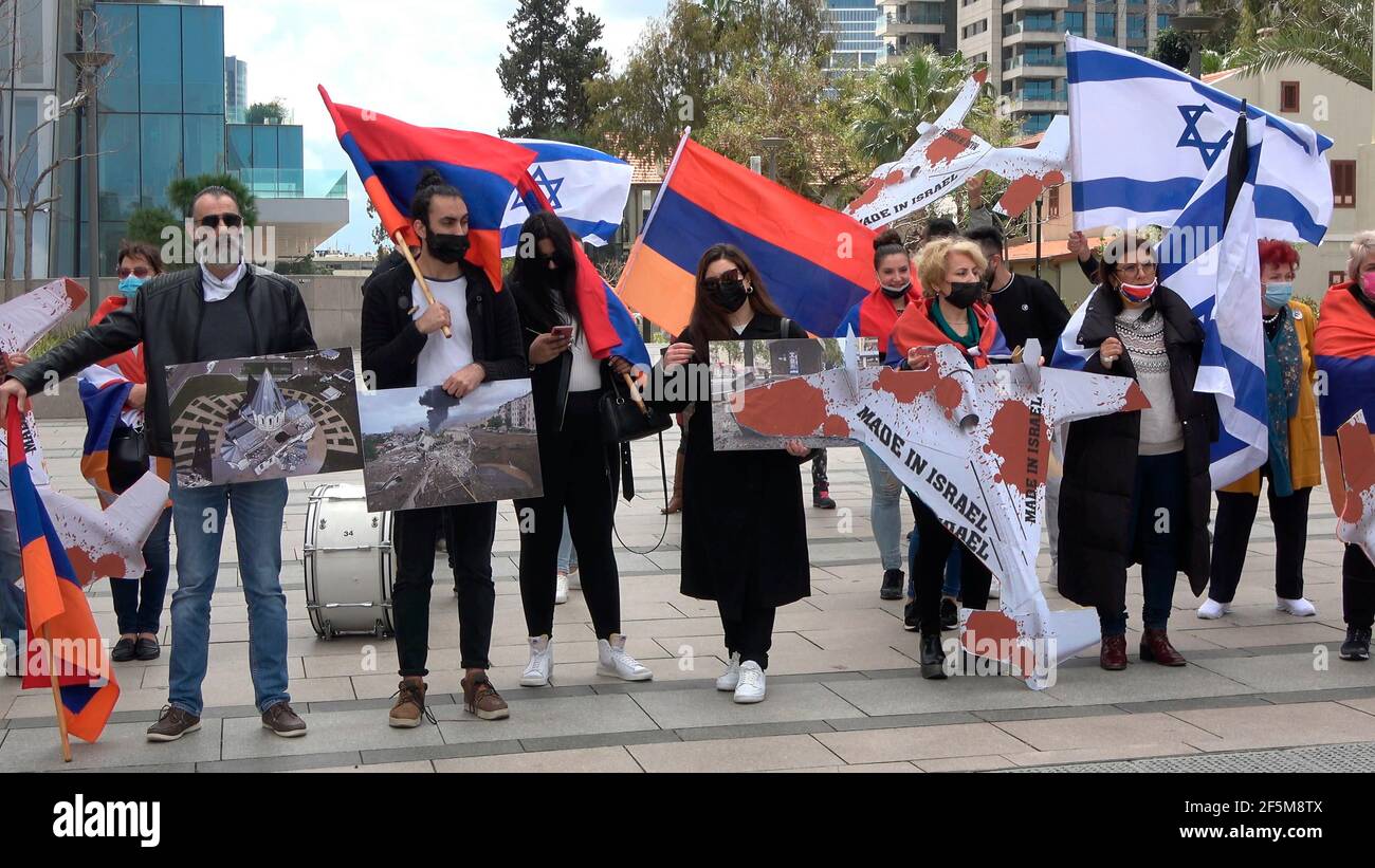 Members of the Armenian community hold photographs of sites in Nagorno Karabakh after they were hit by Azeri army and mock drones during a protest against Israeli weapon sales to Azerbaijan in front of Israel's Defense Ministry on March 26, 2021, in Tel Aviv, Israel. Israel has been accused by Armenia and Armenian supporters of being complicit in Azerbaijan’s policy and knowingly selling drones used to attack civilian populations in the disputed territory of Nagorno-Karabakh during the latest war between Azerbaijan and Armenia. Stock Photo