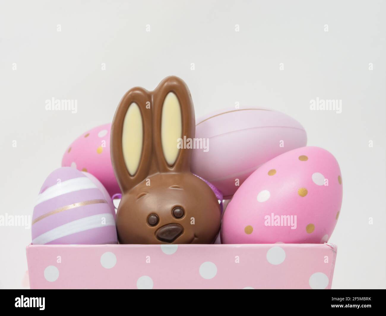 Closeup of a happy chocolate Easter bunny hidden among Easter eggs