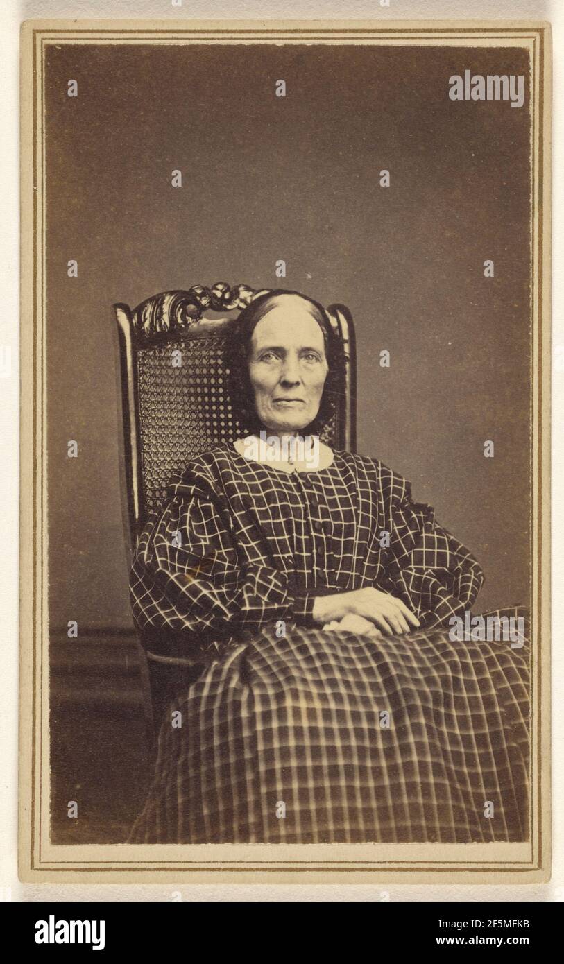 Unidentified woman wearing a checkered dress, seated in a wicker chair. Abraham F. Burnham (American, active 1880s - 1890s) Stock Photo