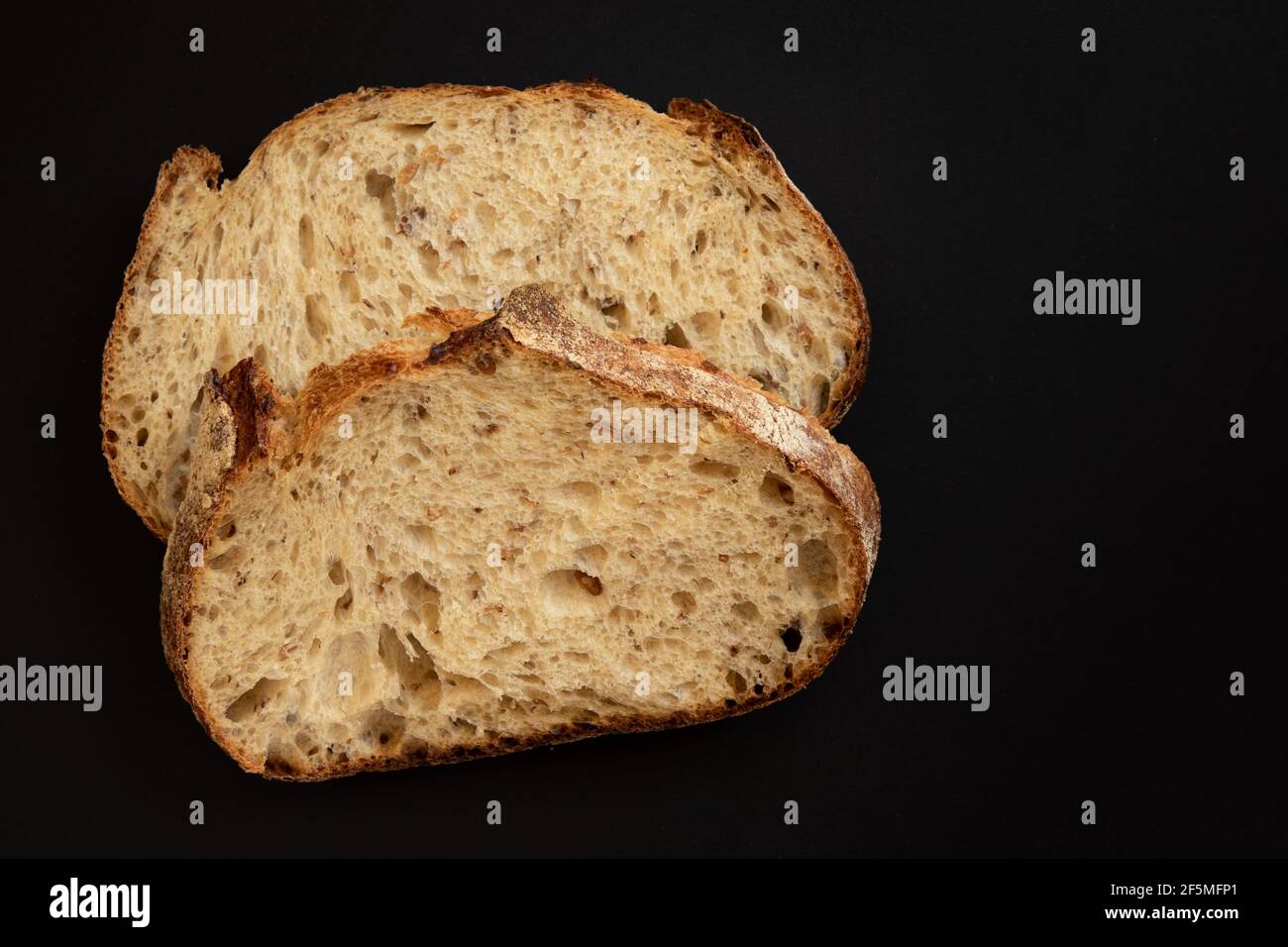 Fresh sliced whole grains bread on a black background. Two slices of sliced bread. View from above. Stock Photo