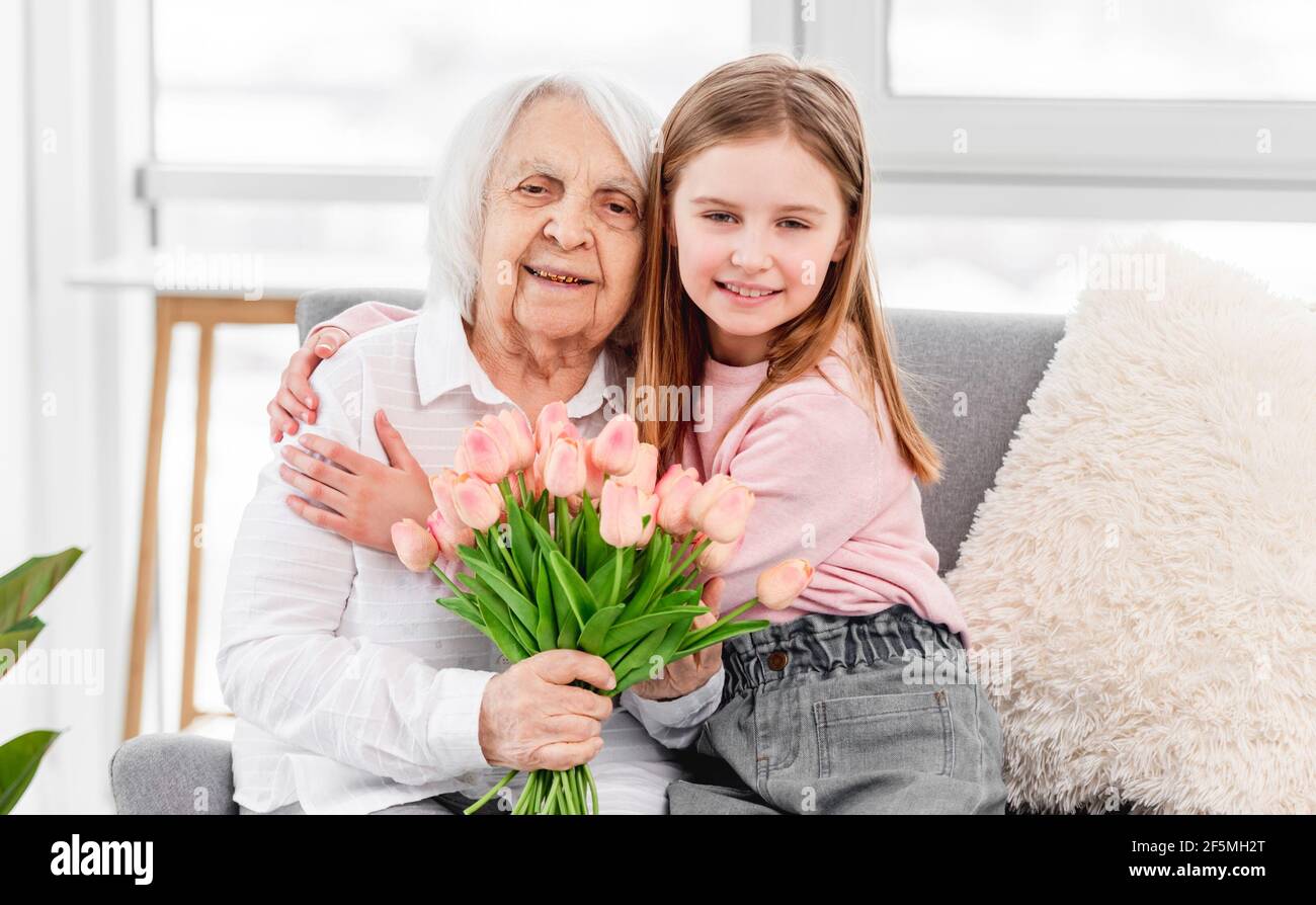 Grandaughter gives flowers to grandmother Stock Photo Alamy