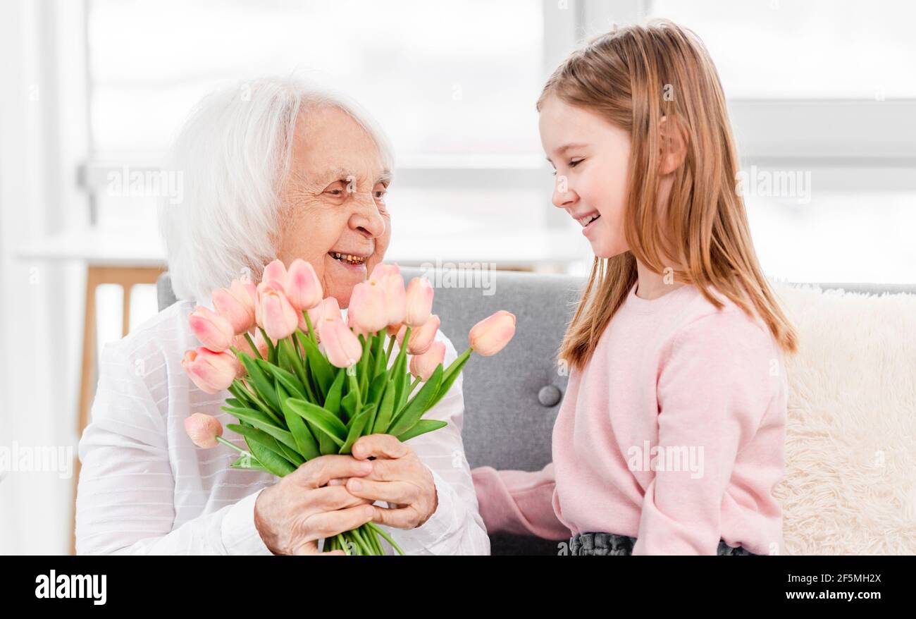 Grandaughter gives flowers to grandmother Stock Photo Alamy