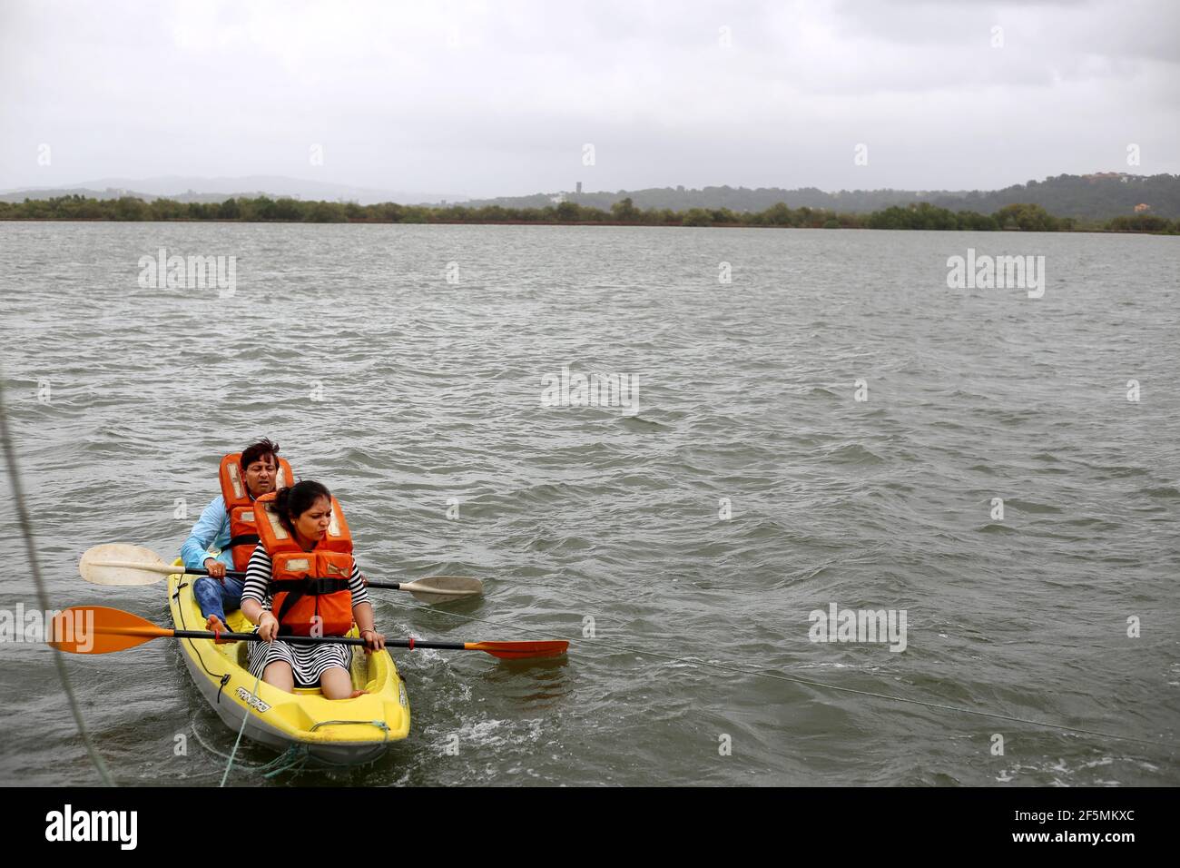 Two people rowing on the Mandovi River, Goa, India Stock Photo