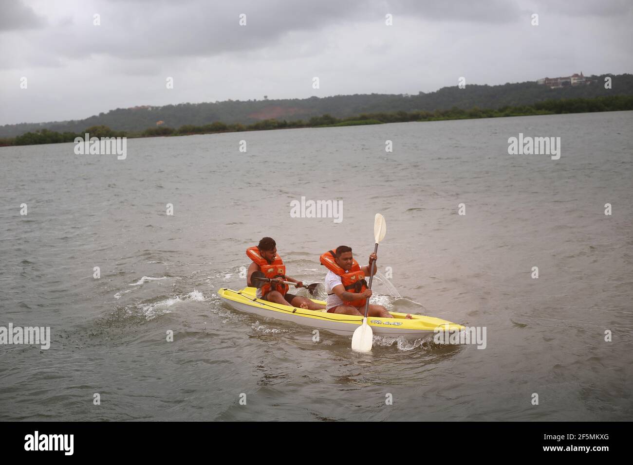 Two young men rowing on the Mandovi River, Goa, India Stock Photo