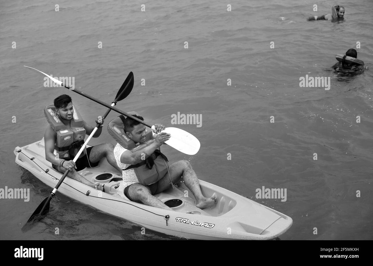 Two young men rowing on the Mandovi River, Goa, India Stock Photo