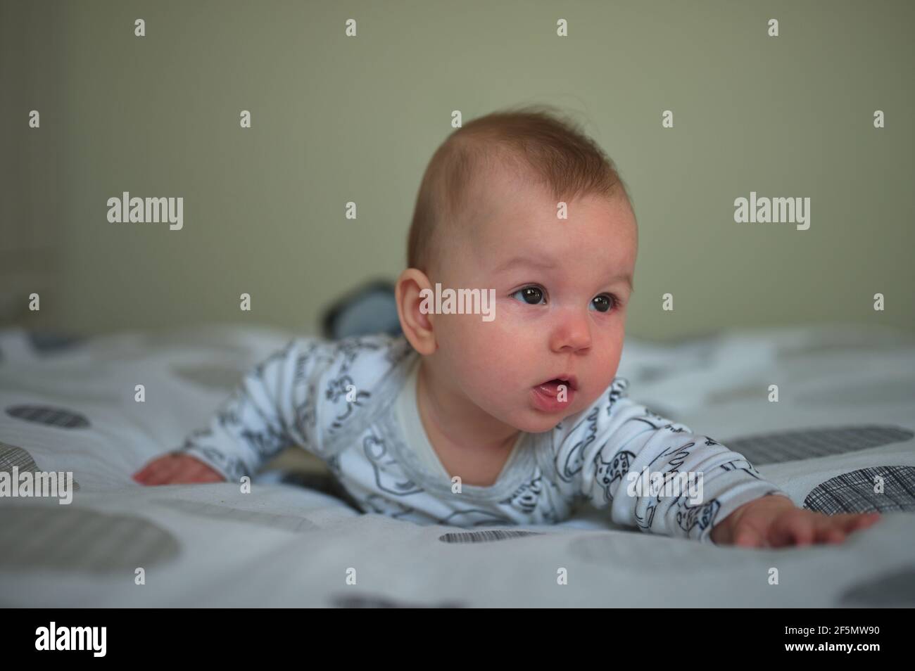 Newborn baby in pajamas relaxing in bed Stock Photo Alamy