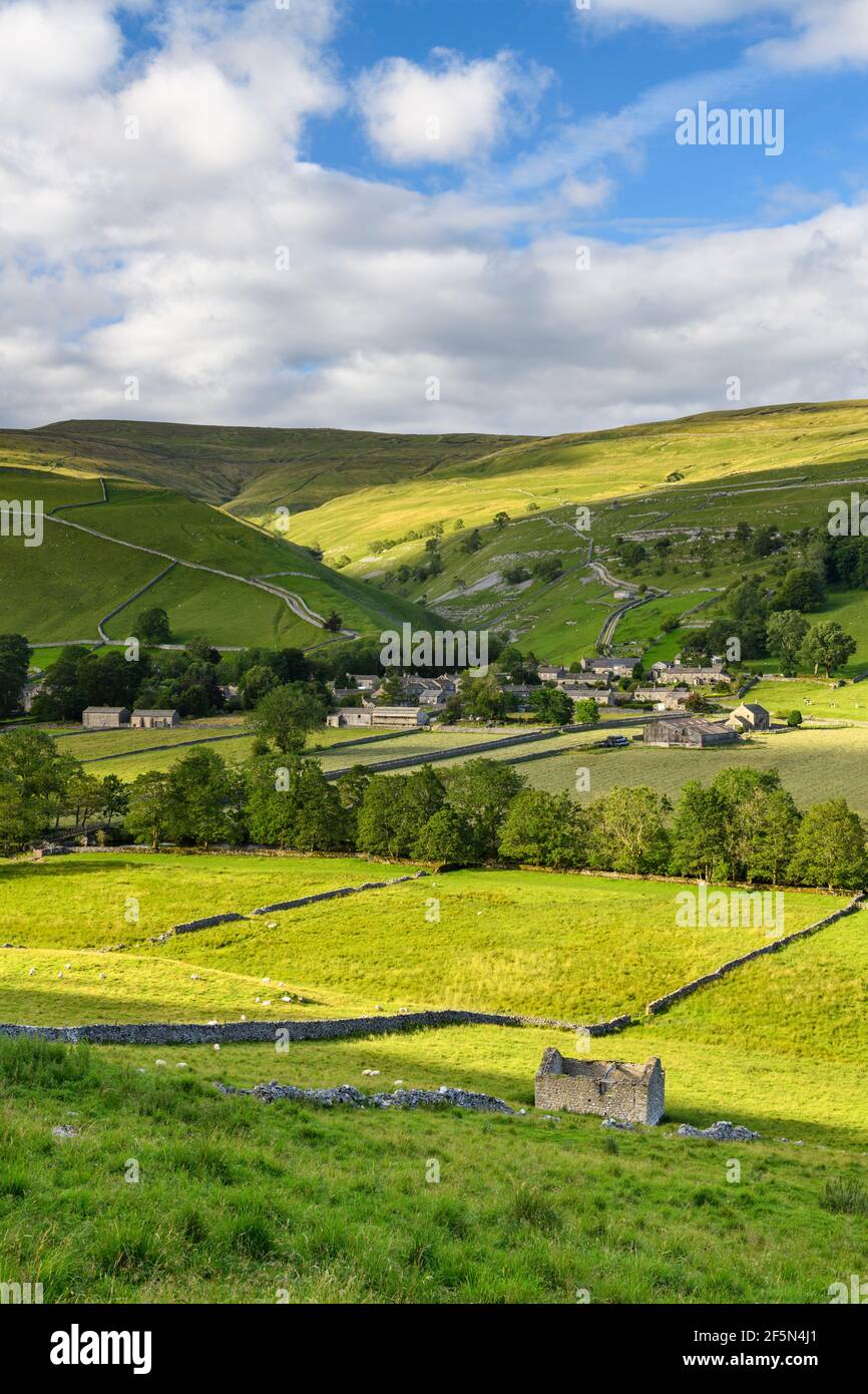 Picturesque Dales village houses, nestling in sunlit valley, fields, hills, hillsides, field walls & old barn ruin - Starbotton, Yorkshire England UK. Stock Photo