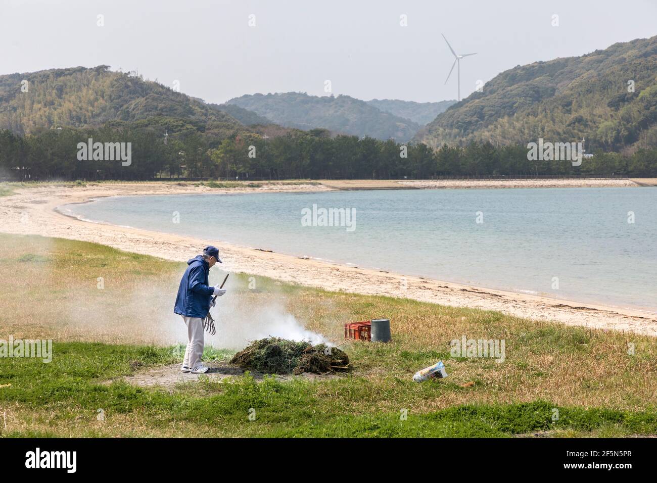 Man burning seaweed to clear up the beach at Agawa Hosenguri seaside park, Japan Stock Photo