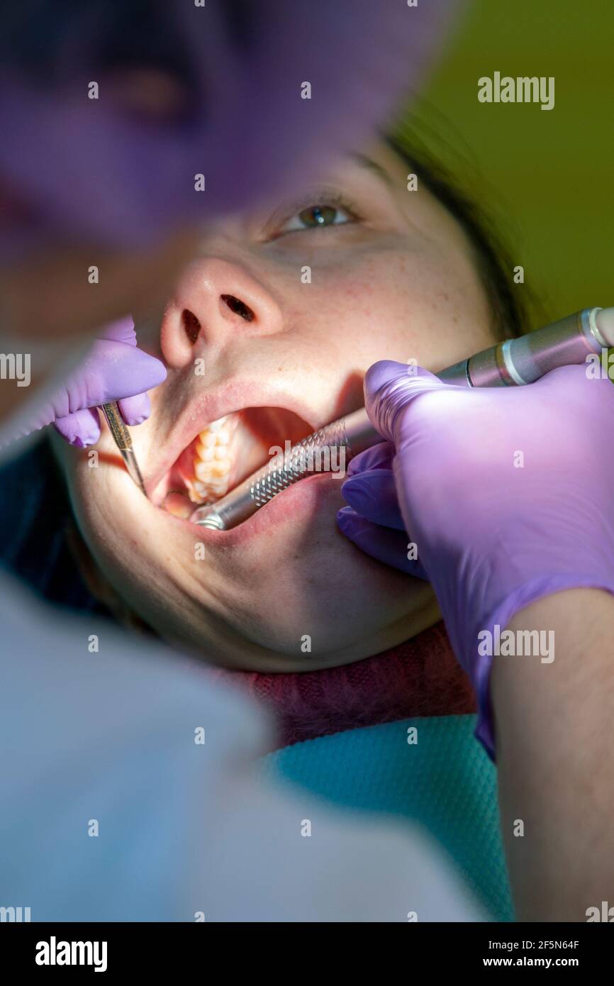 Male dentists examining and working on young female patient.Dentist's office. Real woman in a chair at the dentist. close up. toned Stock Photo