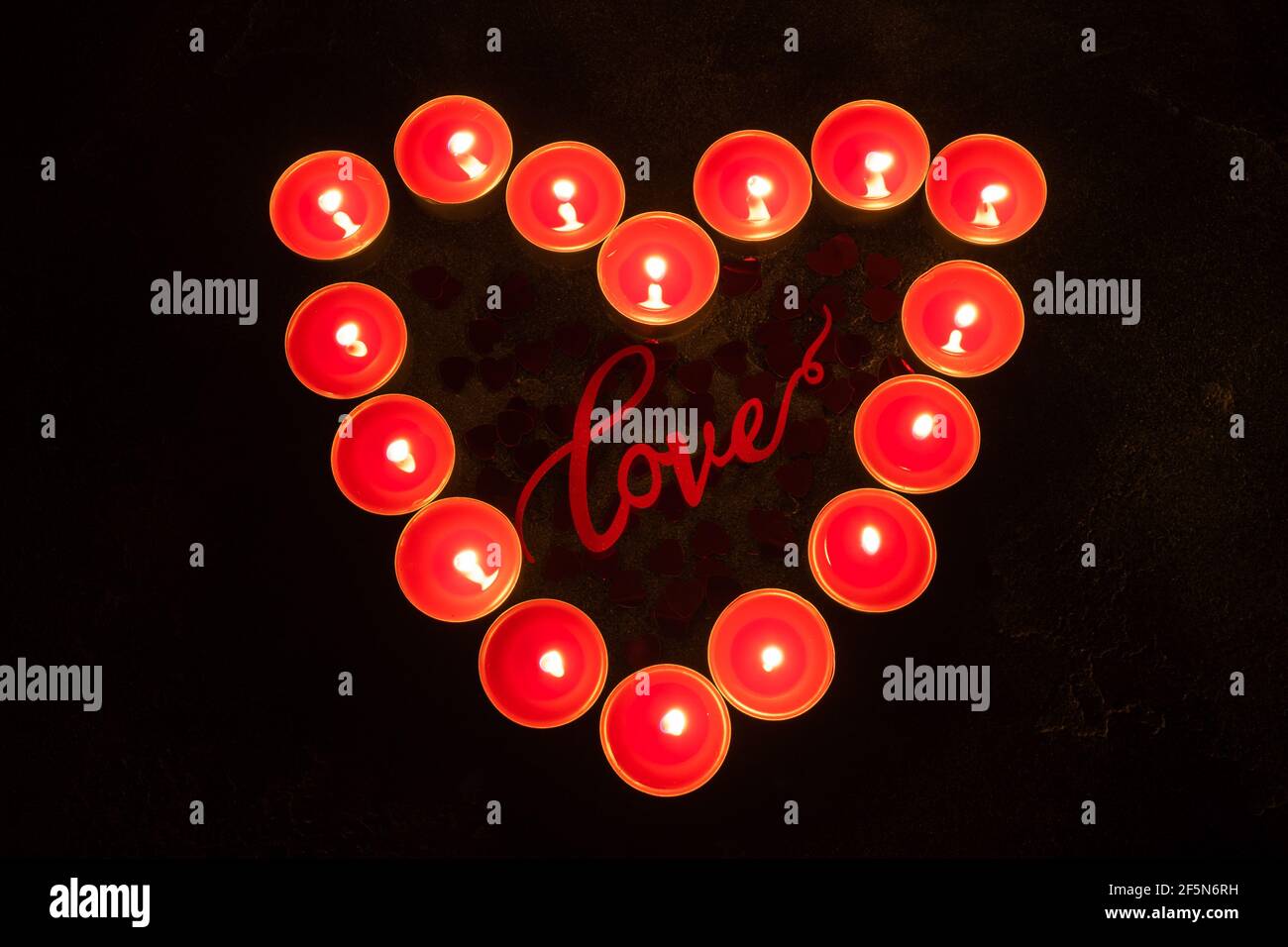 Red candles in the shape of heart on black background, concept of Valentine's Day Stock Photo