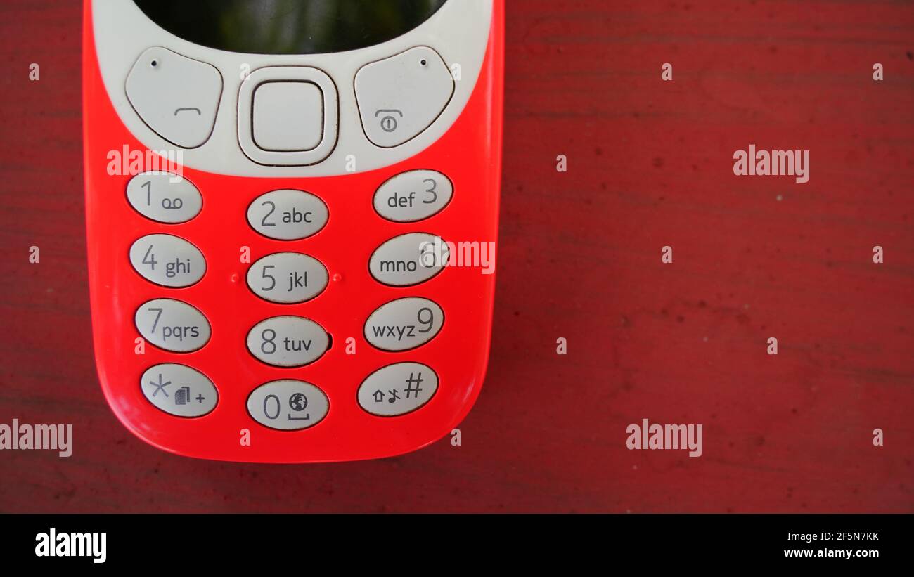 Old nokia 3310 keypad phone isolated on wooden table background. Old Classic mobile cell phone with small screen. Nokia branded company in India. Stock Photo