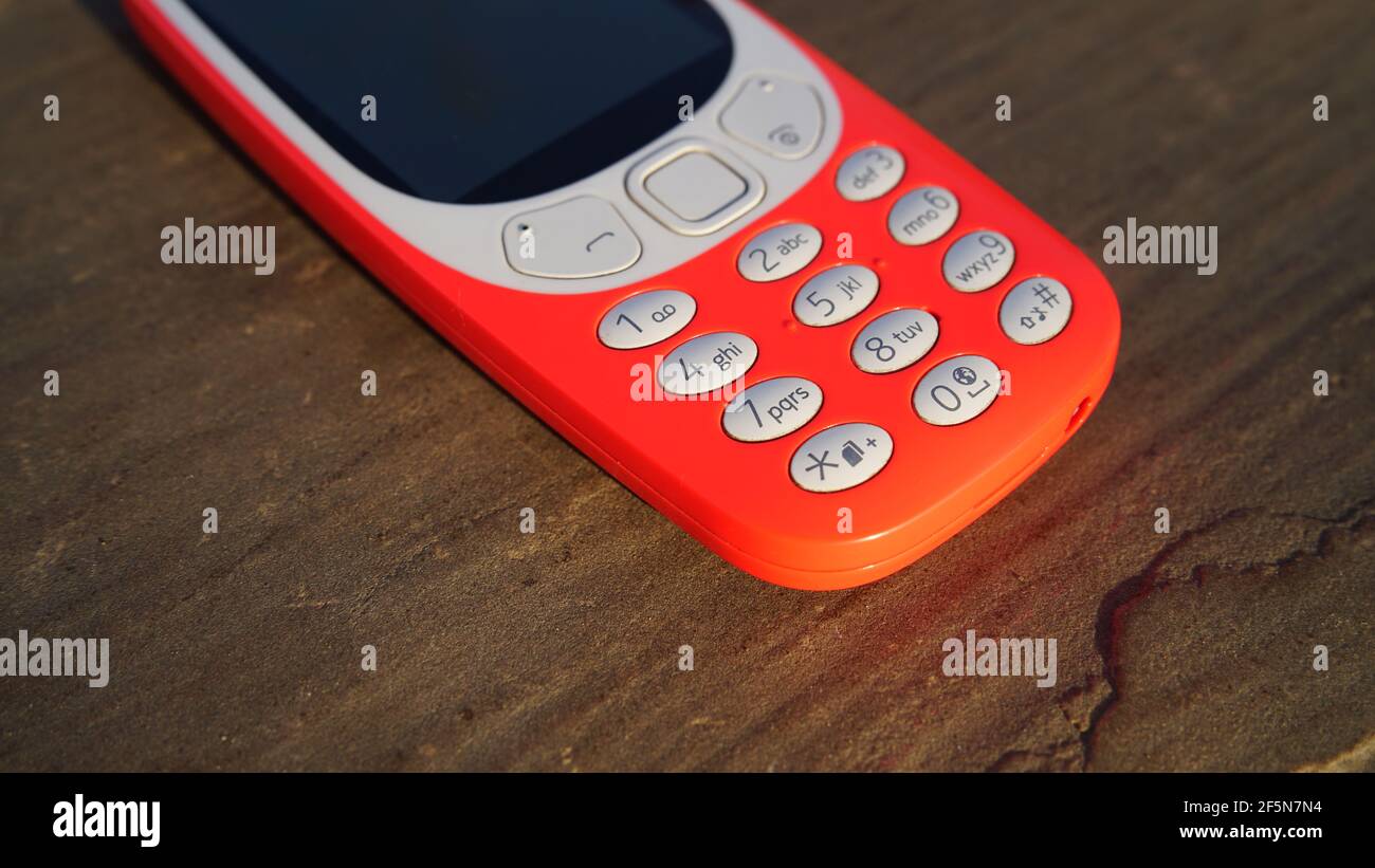 Old nokia 3310 keypad phone isolated on wooden table background. Old Classic mobile cell phone with small screen. Nokia branded company in India. Stock Photo