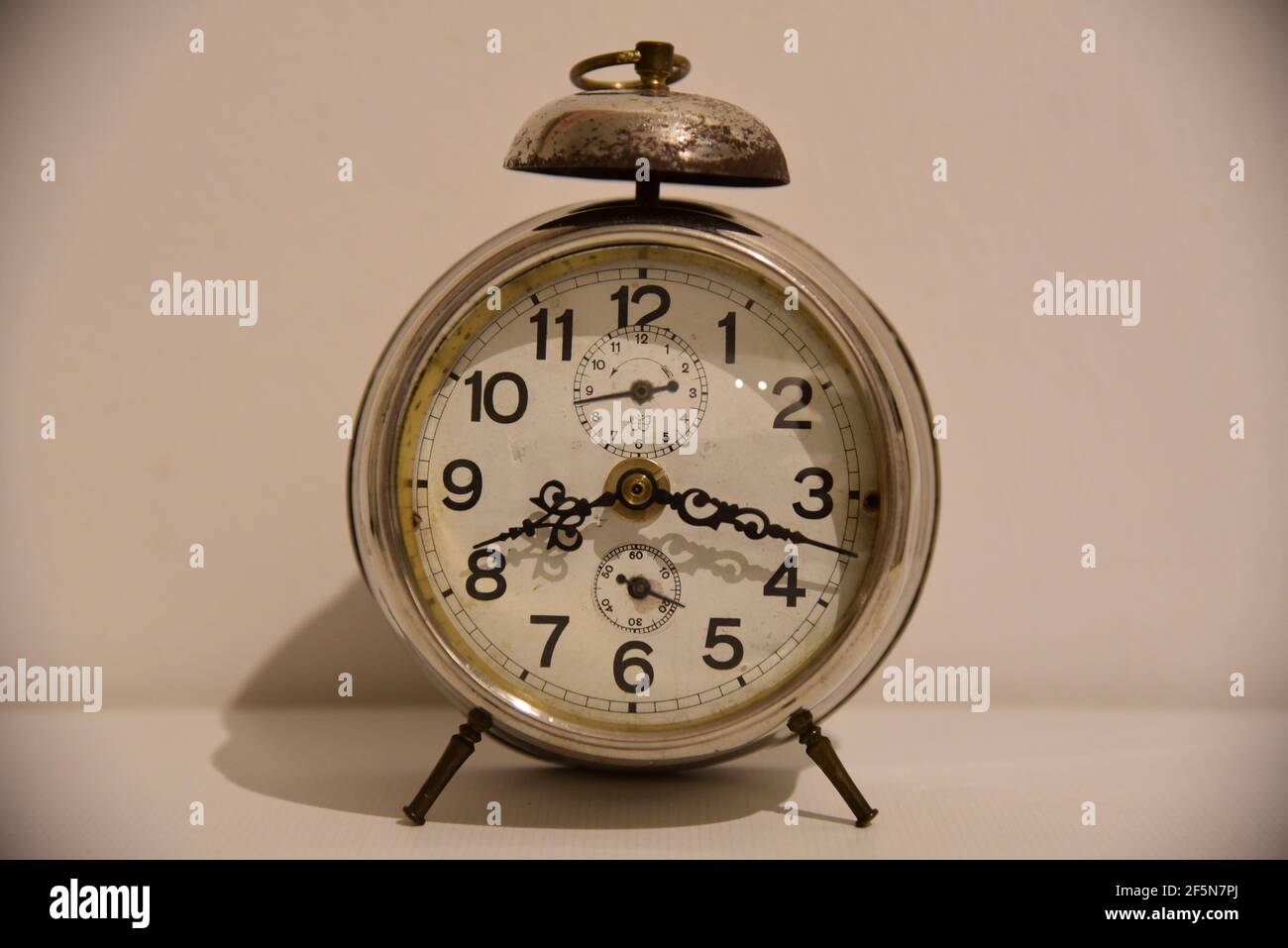 an antique clock in front of a white wall Stock Photo Alamy