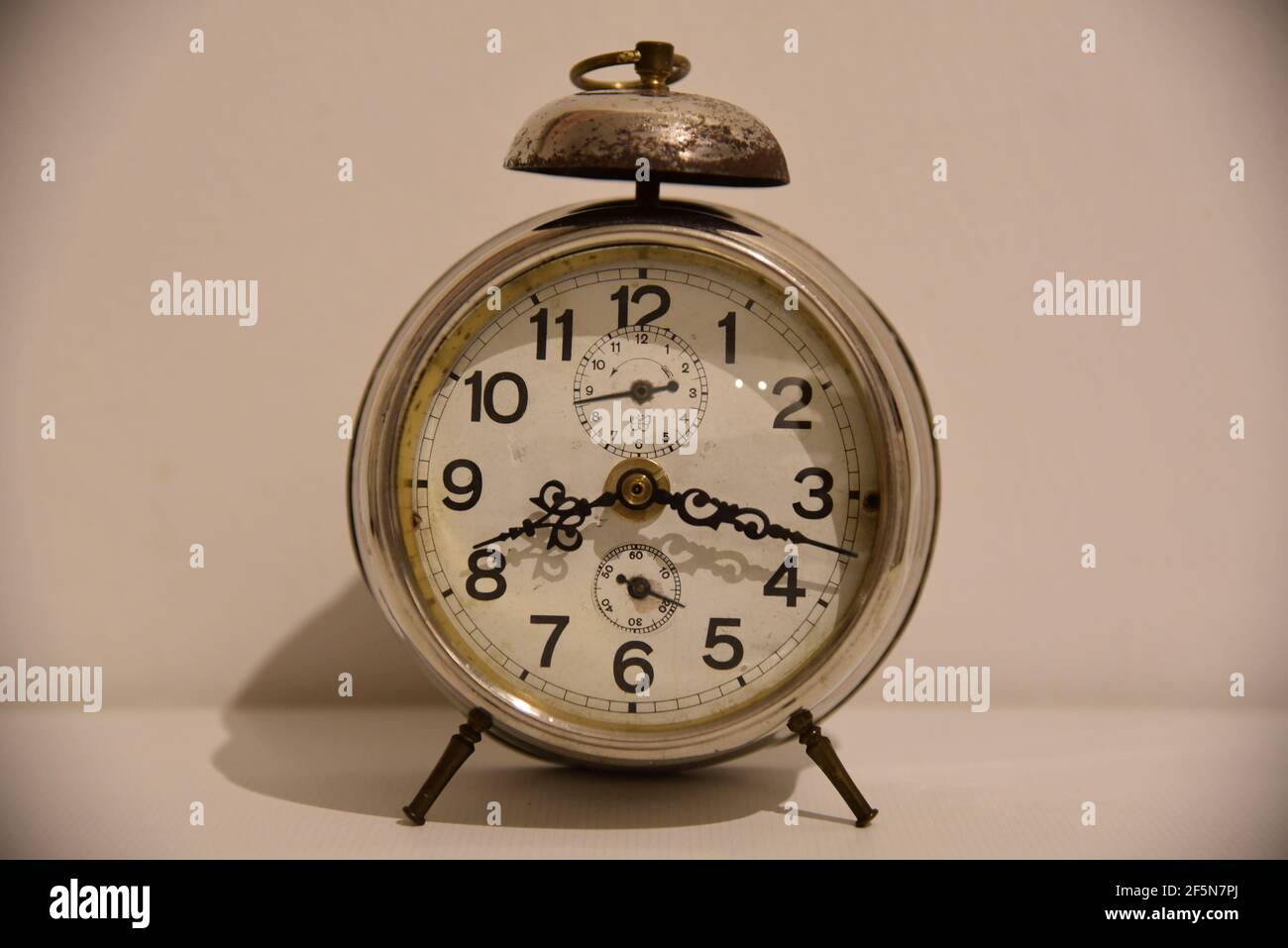 an antique clock in front of a white wall Stock Photo