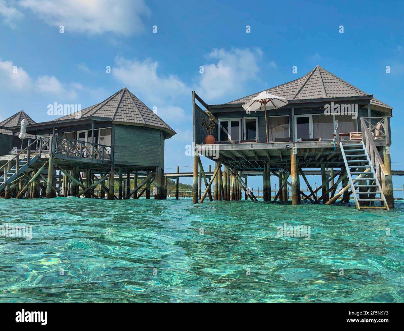 Wooden Water Villa with Turquoise Ocean in Maldives. Beautiful View of Overwater Bungalows with Laccadive Sea in Maldivian Resort Komandoo. Stock Photo