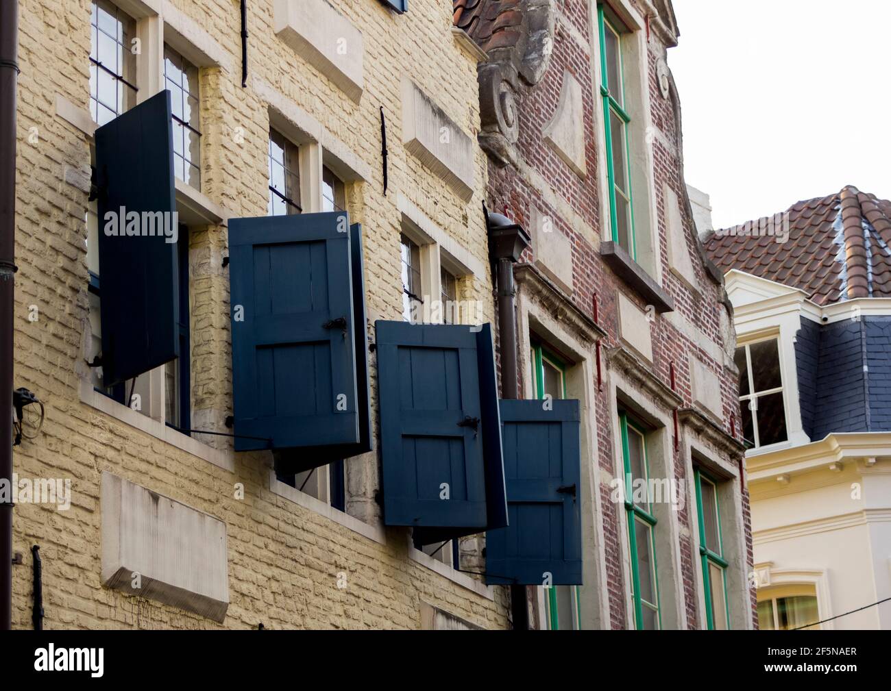Upstairs windows with blue shutters on an old yellow, brick building in the Patershol district of Ghent, Belgium Stock Photo
