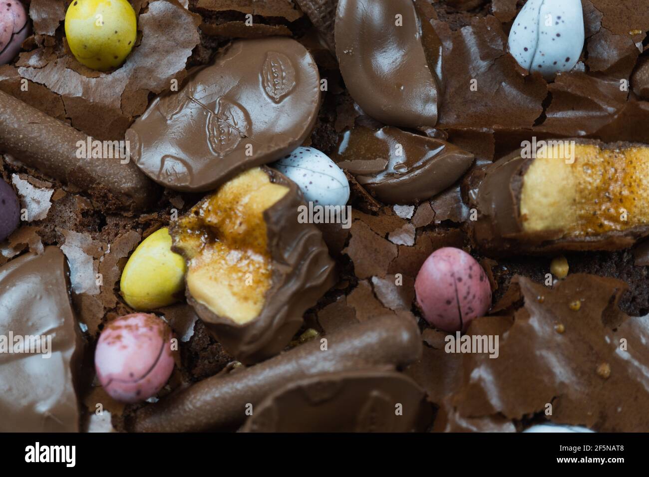 Home baking Easter concept. Brownie with chocolate bars, mini easter eggs and biscuits baked in. Chocolate feast home baked treat Stock Photo