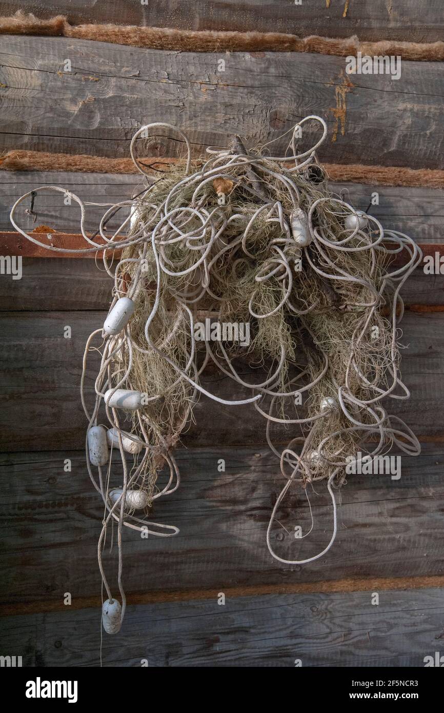 An old fishing net with floats hanging on a log wall. Close up