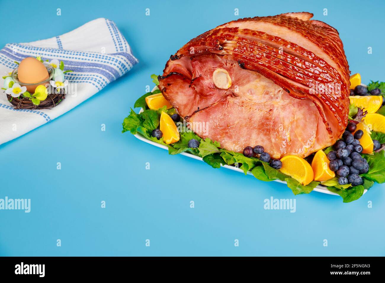 Spiral sliced and glazed ham on blue table. Stock Photo