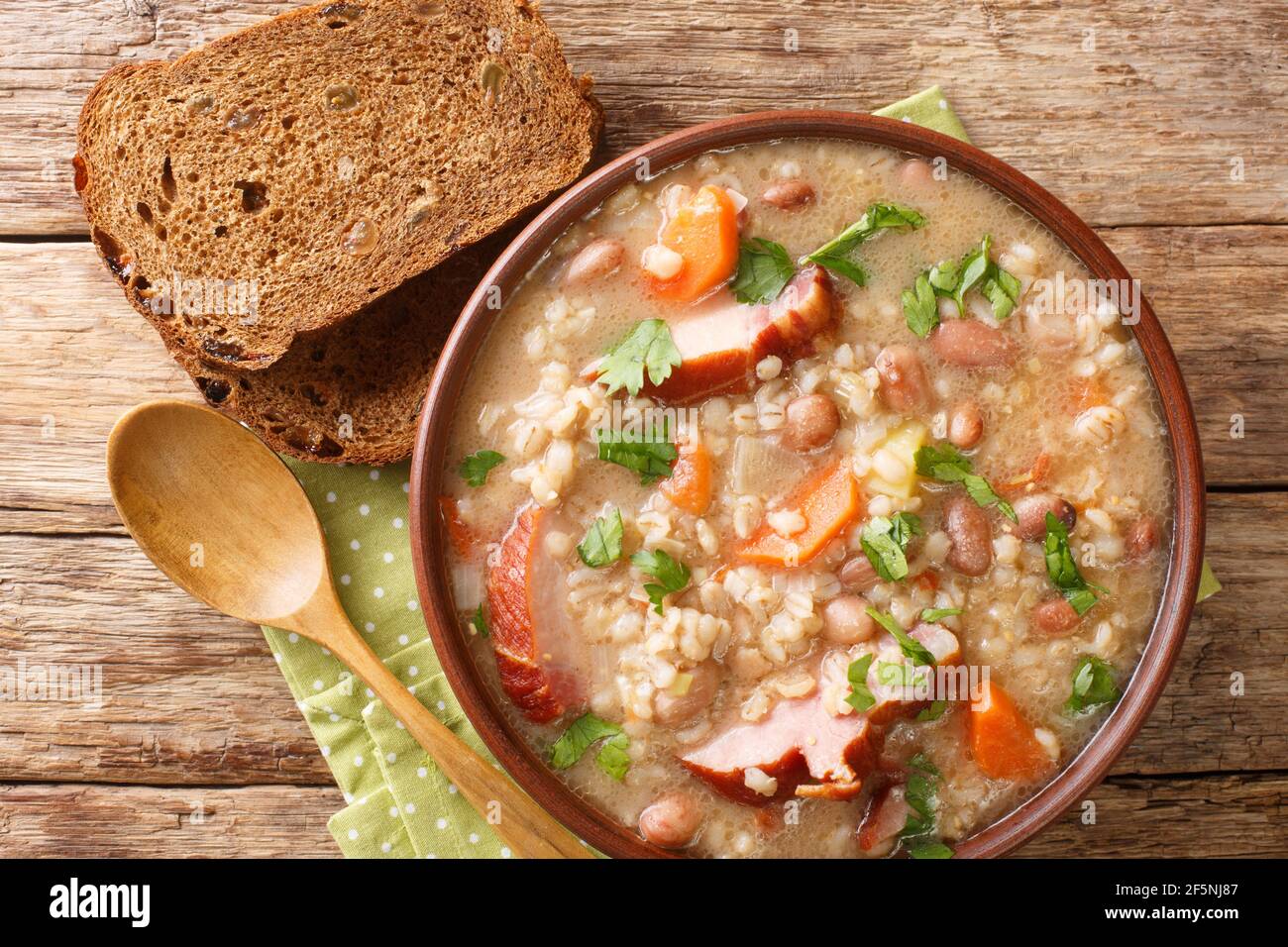 Thick rich barley and bean soup with smoked meat and vegetables close-up in a bowl on the table. horizontal top view from above Stock Photo