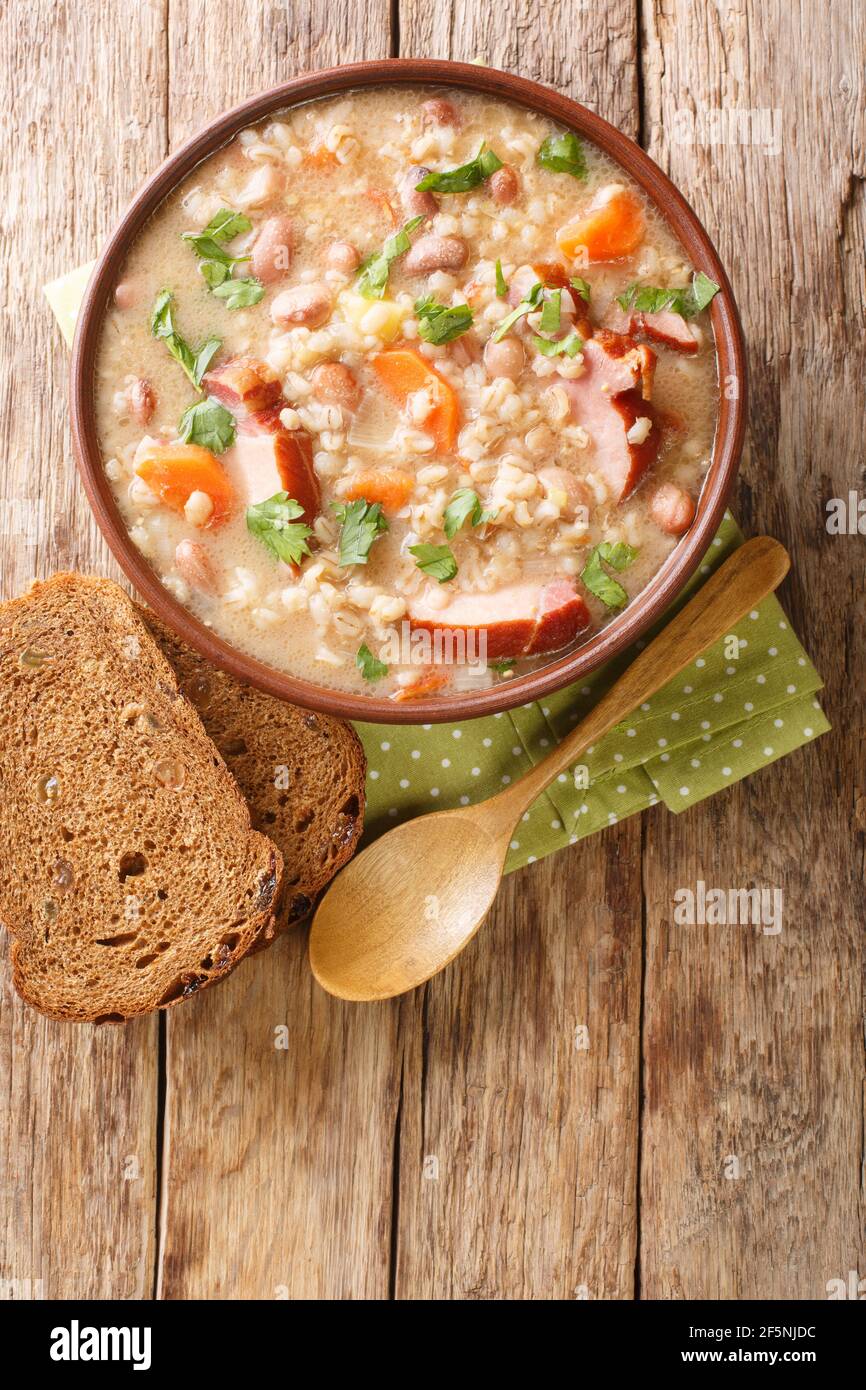 Ricet barley and bean soup with smoked meat and vegetables close-up in a bowl on the table. vertical top view from above Stock Photo