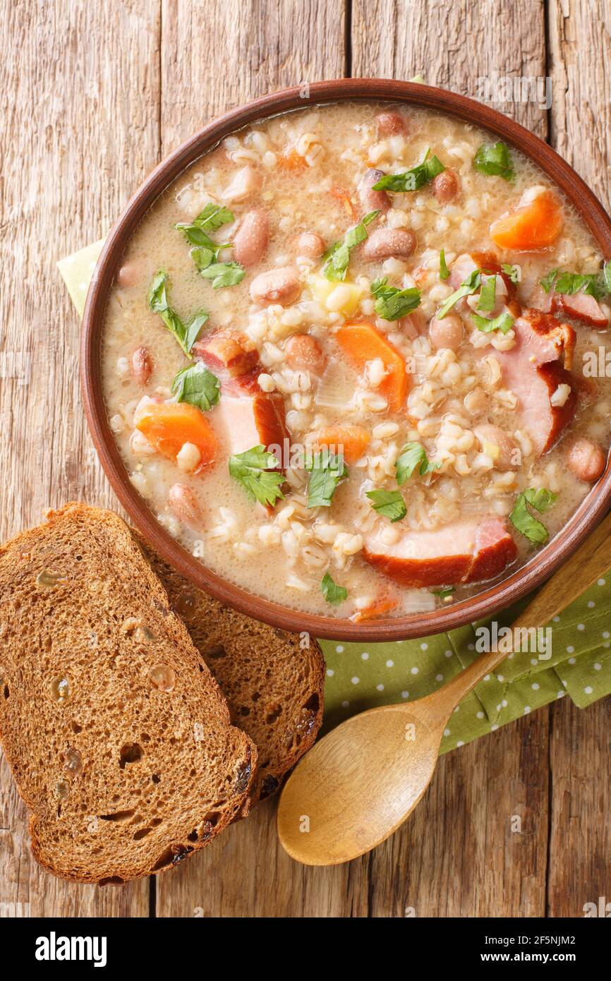Slovenian barley and bean soup with smoked meat close-up in a bowl on the table. vertical top view from above Stock Photo