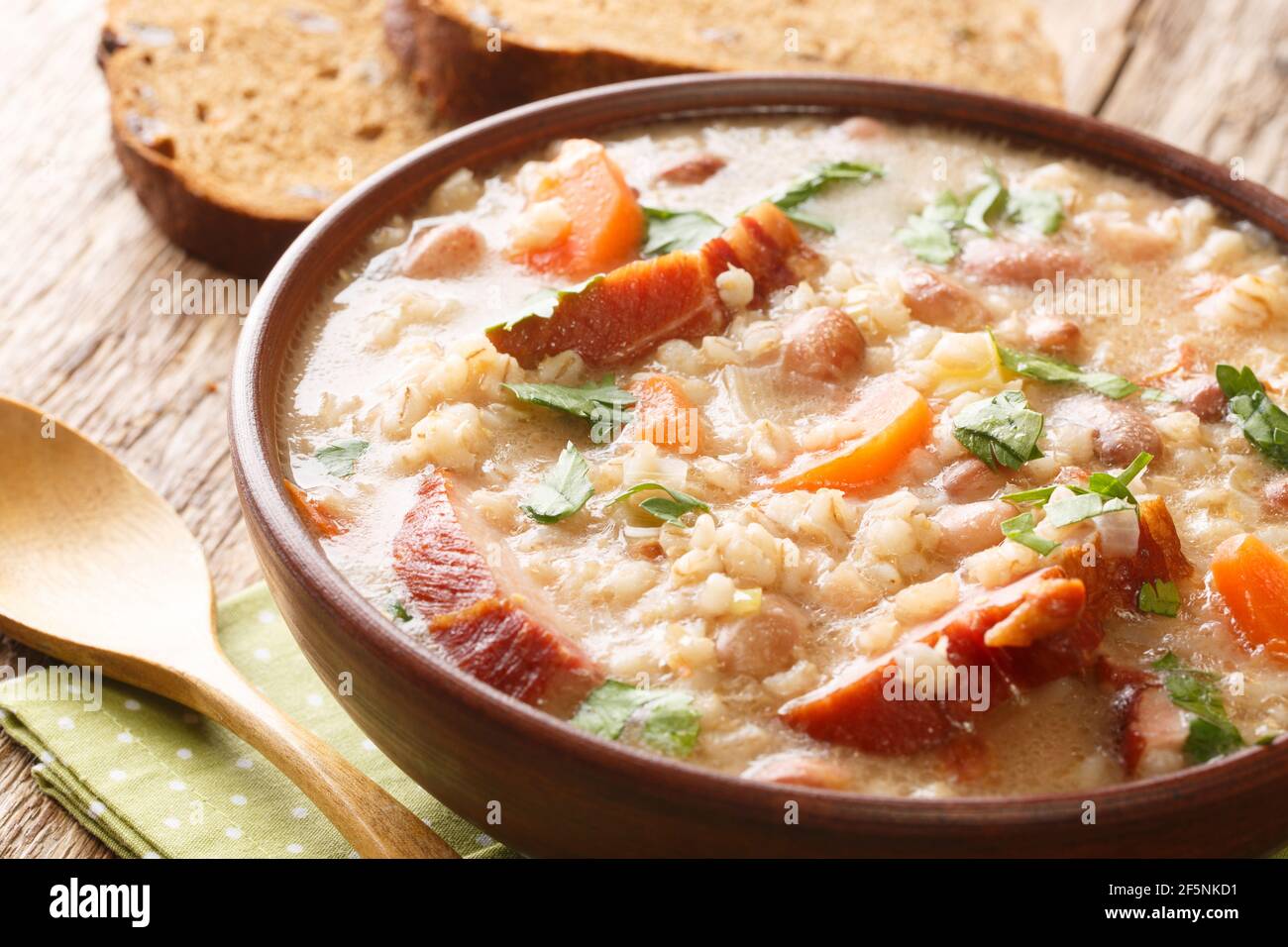 Thick rich barley and bean soup with smoked meat and vegetables close-up in a bowl on the table. horizontal Stock Photo