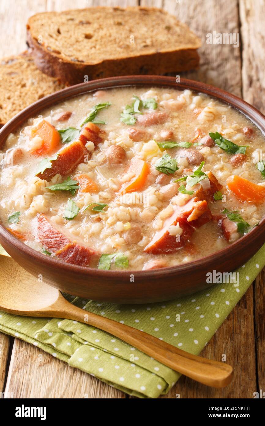 Ricet barley and bean soup with smoked meat and vegetables close-up in a bowl on the table. vertical Stock Photo