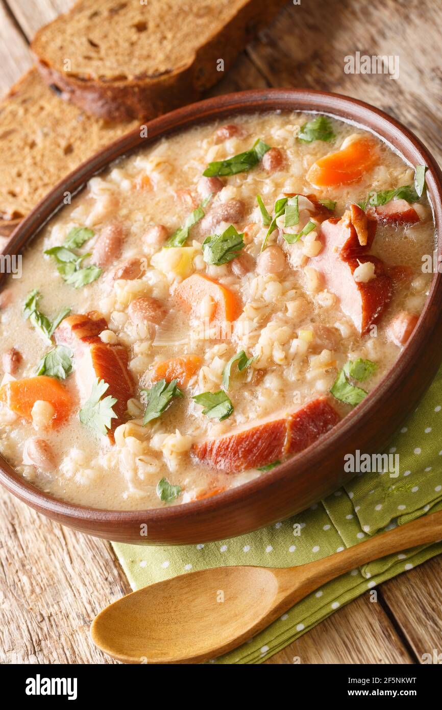 Slovenian barley and bean soup with smoked meat close-up in a bowl on the table. vertical Stock Photo