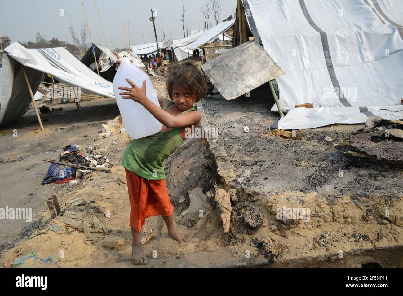 Children are seen taking drinking water for her family which supplied by NGOs, after a fire at a refugee camp in Ukhia, in the southeastern Cox's Baza Stock Photo