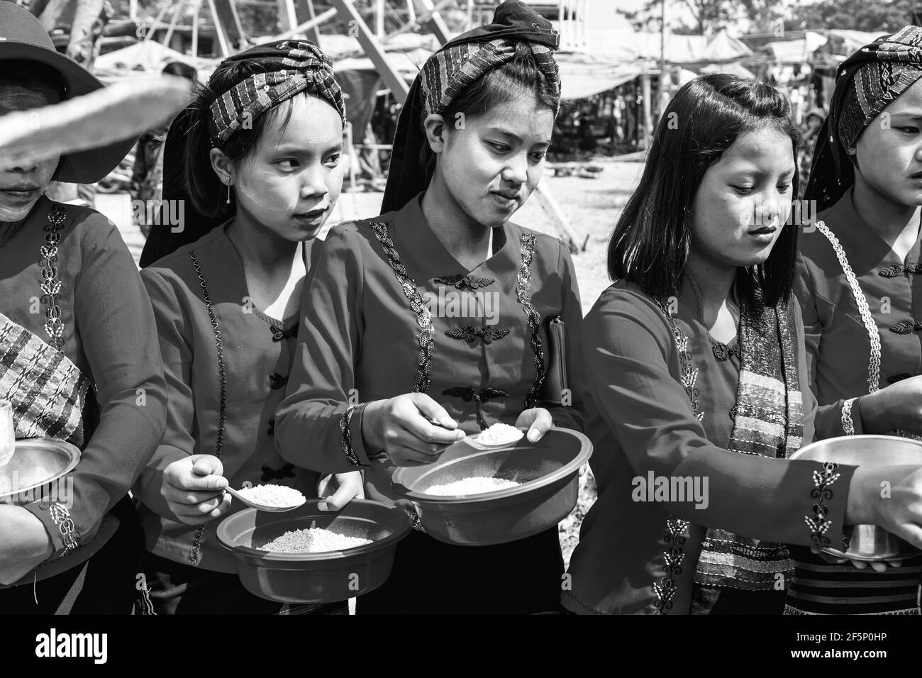 Young Ethnic Minority Women Giving Alms To Monks Who Are Taking Part In A Procession During The Pindaya Cave Festival, Pindaya, Shan State, Myanmar. Stock Photo