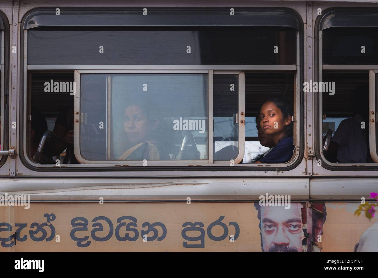 Weligama, Sri Lanka - March 28 2019: Local Sri Lankan women passengers make eye contact out a public transport bus window in Weligama, Sri Lanka. Stock Photo