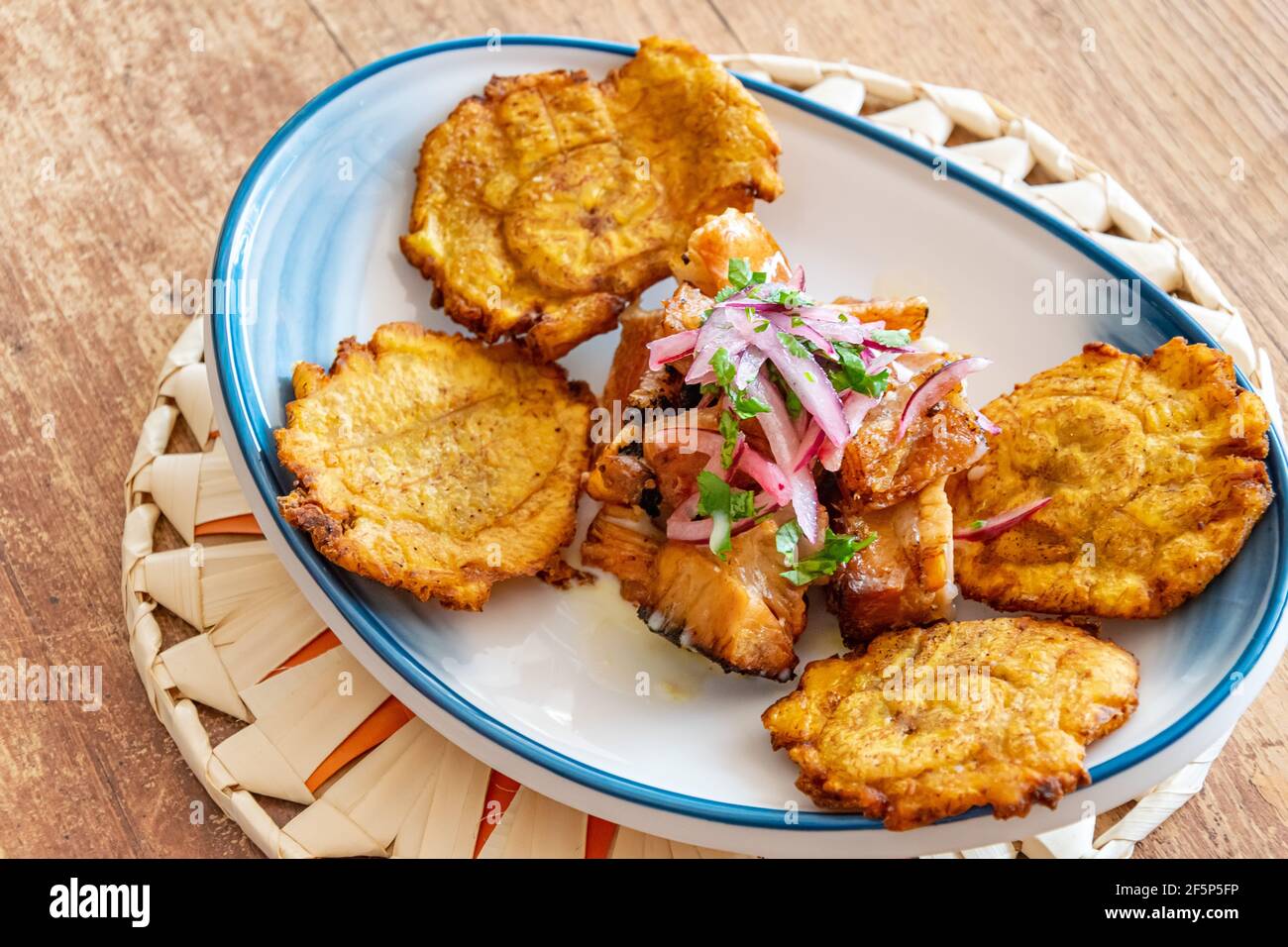 a plate of fried plantain served with shredded beef drizzled with onion and lime dressing Stock Photo