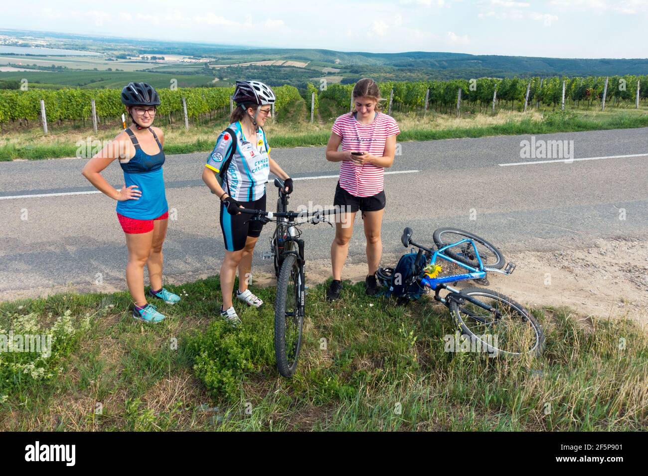 Three young women on bicycle, rest by the roadside bike Stock Photo