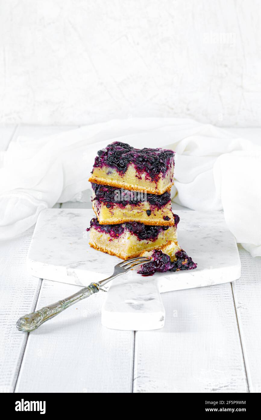 Three pieces of blueberry cake on a white marble cutting board and white wood table Stock Photo