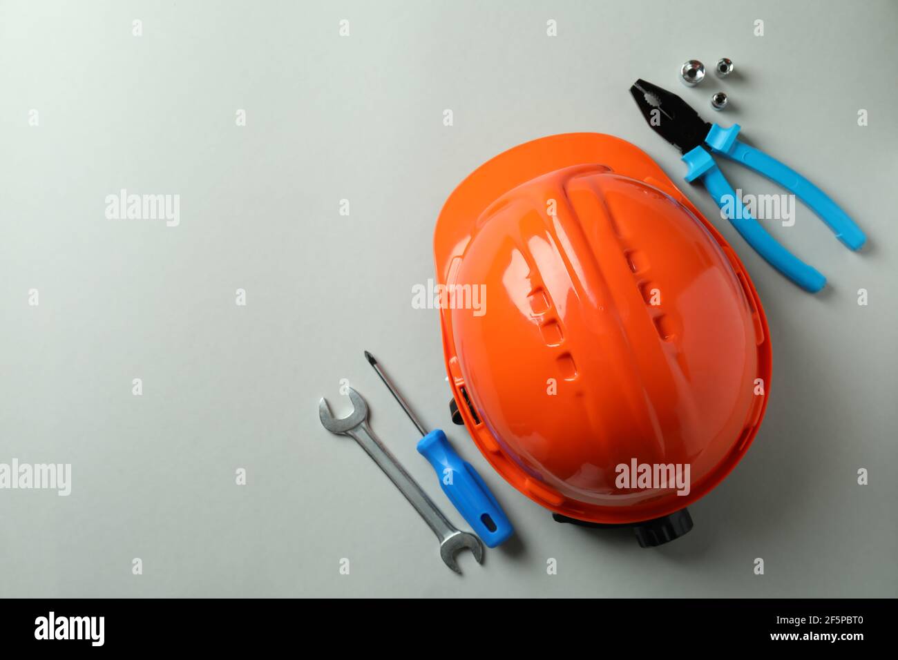 Hard hat and working tools on light gray background Stock Photo