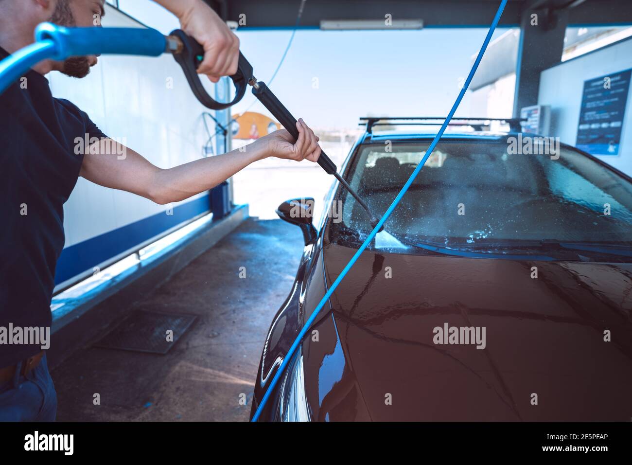 Man washing car in self serve car wash. Cleaning car using high