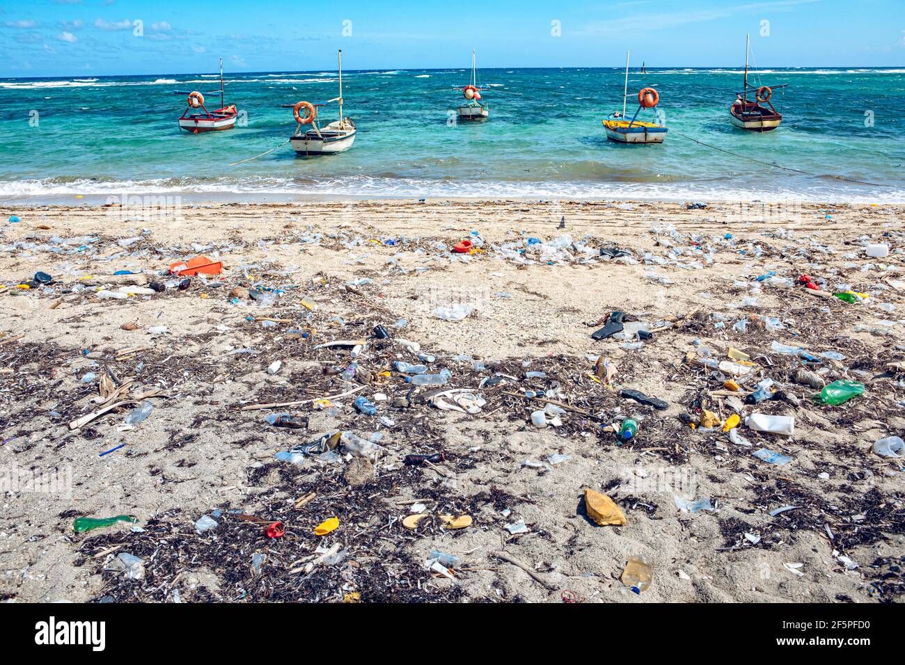 heavy plastic pollution on the beach of tropical sea. Waste on beach with blue sea background. (Cuba) Stock Photo