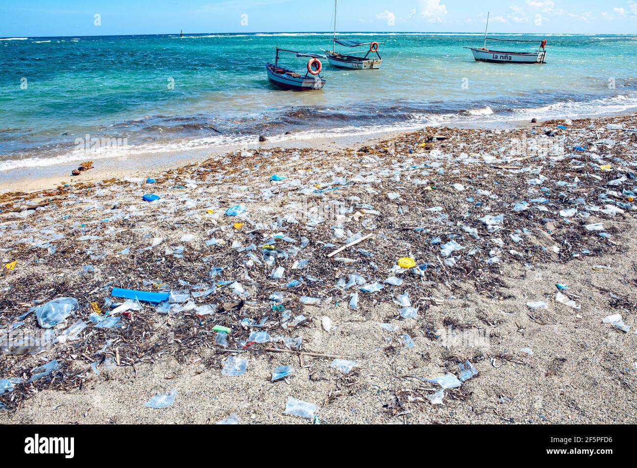 heavy plastic pollution on the beach of tropical sea. Waste on beach with blue sea background. (Cuba) Stock Photo