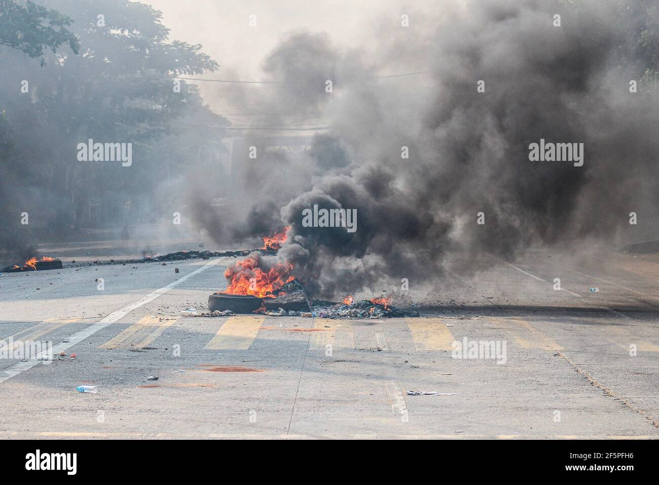 Burning tires seen in the middle of the street to block police and military from reaching the anti-democracy protesters during a protest against the military coup.Myanmar police and military soldiers (tatmadow) attacked protesters with rubber bullets, live ammunition, tear gas and stun bombs in response to anti-military coup protesters on Saturday, killing more than 90 people and injured many others. At least 300 people have been killed in Myanmar since the 1 February coup, a UN human rights official has said. Myanmar's military detained State Counsellor of Myanmar Aung San Suu Kyi on February Stock Photo