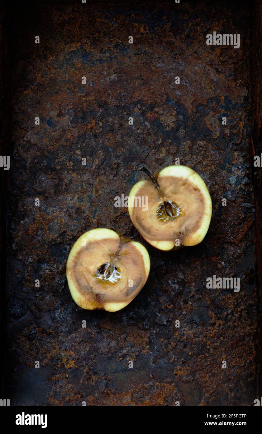 2 halves of rotten apple on rusty metal Stock Photo