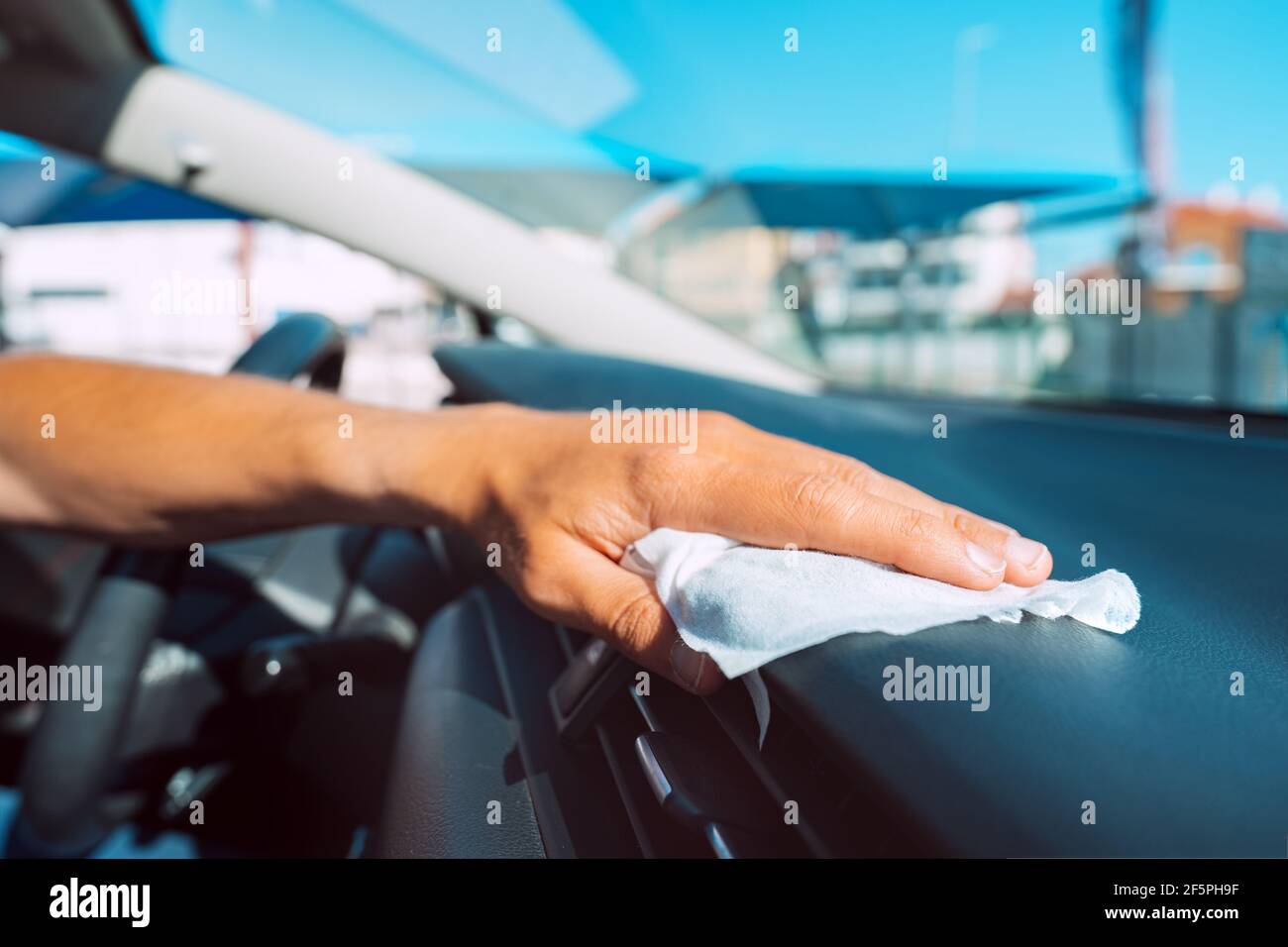 Closeup of man hand with antivirus antibacterial wet wipe or napkin cleaning car panel. Man disinfecting car salon from bacteria and virus Stock Photo