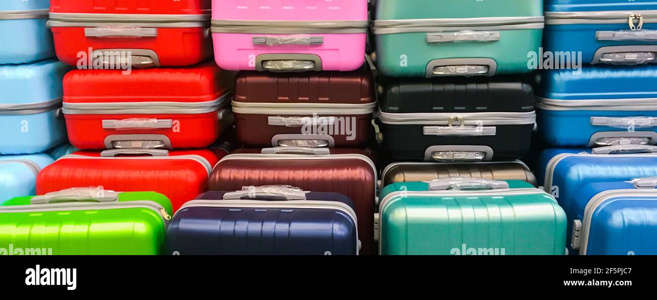 Banner with many new multi-colored large plastic suitcases. Concept of travel, vacation, tourism Stock Photo