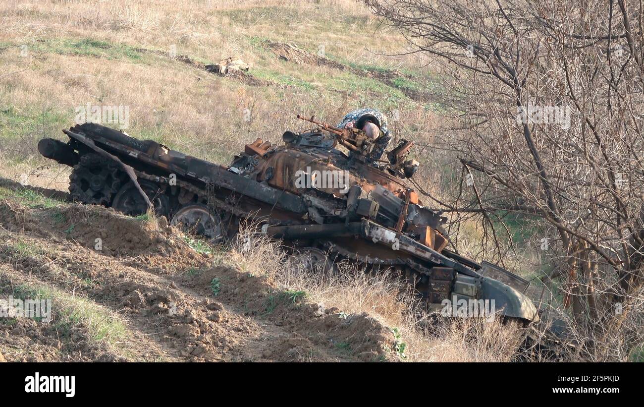 JABRAYIL, AZERBAIJAN - DECEMBER 15: A member of the Russian peacekeeping troops force examines a destroyed Armenian T-72 tank for remains of Armenian fighters killed in the conflict over the disputed region of Nagorno-Karabakh on December 15 2020 in the Jabrayil Rayon of Azerbaijan. Heavy clashes erupted over Nagorno-Karabakh in late September during which more than 5,600 people, including civilians, were killed. The sides agreed to a Russia-brokered cease-fire deal that took effect on November 10 Stock Photo