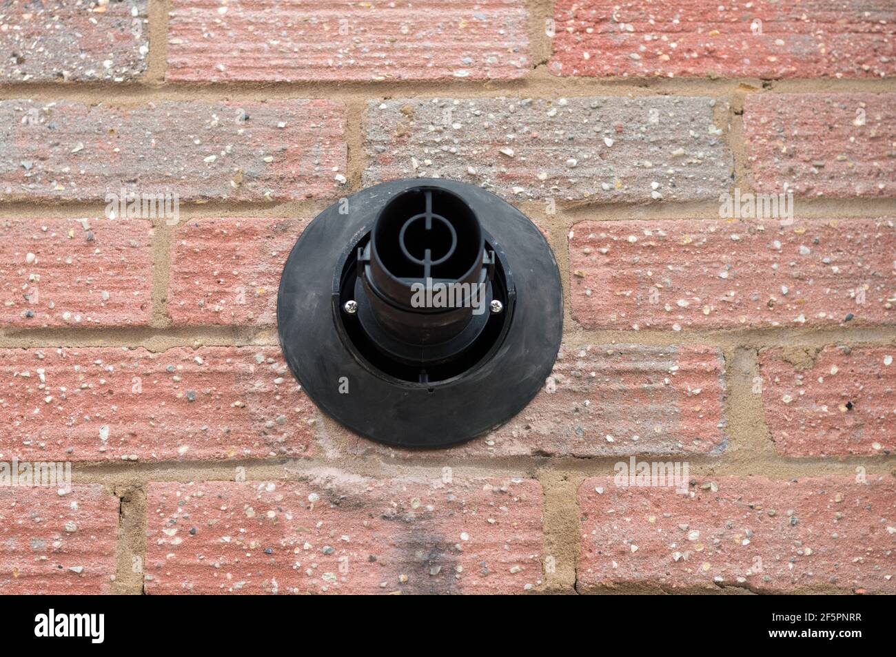 Front view of a gas boiler outlet in a red brick wall Stock Photo - Alamy