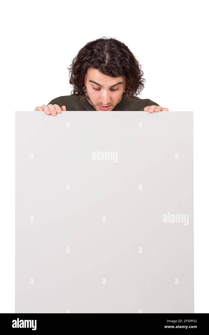 Curious young man, long curly hair style, looks down as holds a blank banner  for announcements. Thoughtful student guy with a copy space sheet for adv  Stock Photo - Alamy