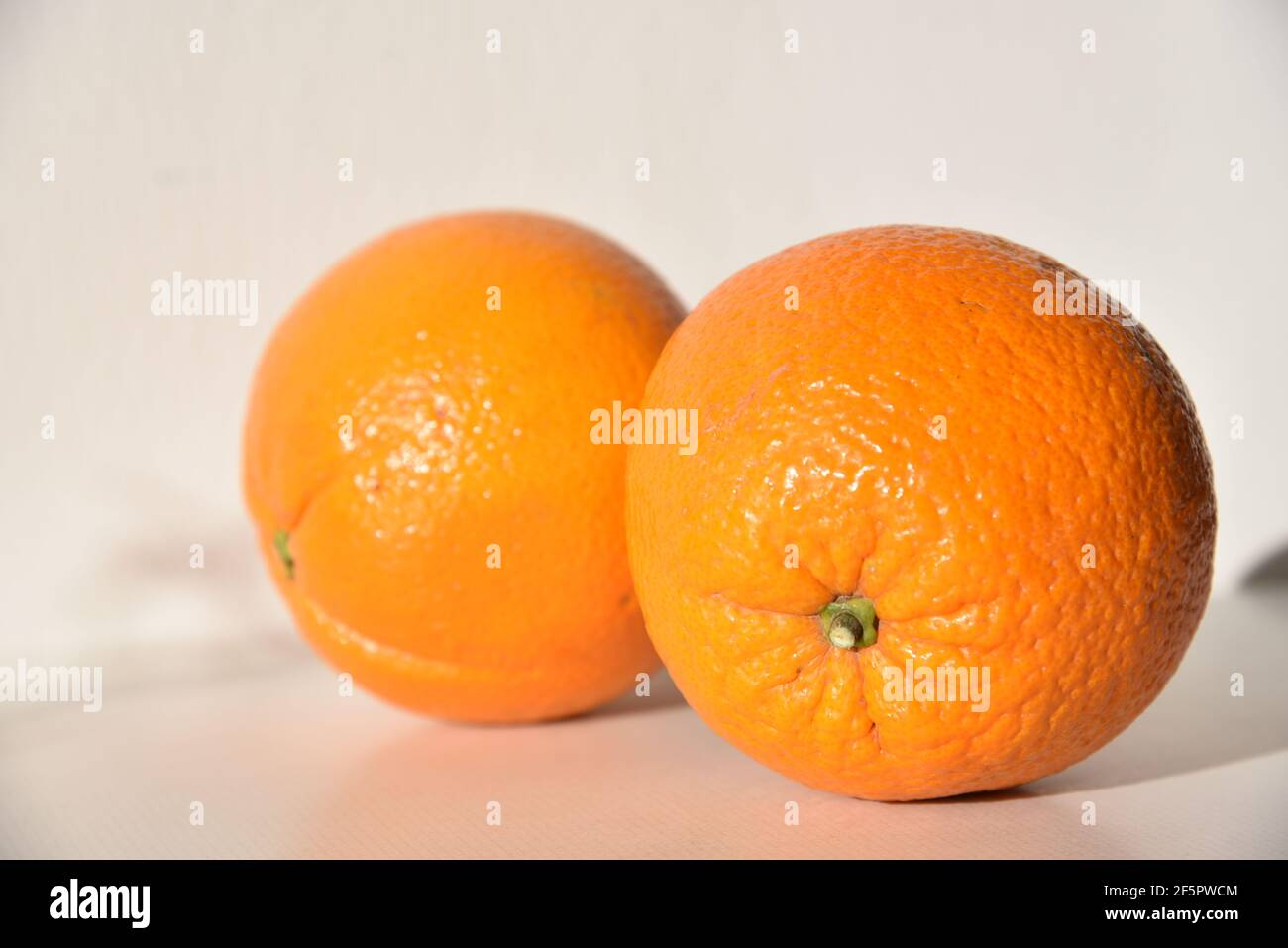 two oranges in front of a white wall Stock Photo - Alamy