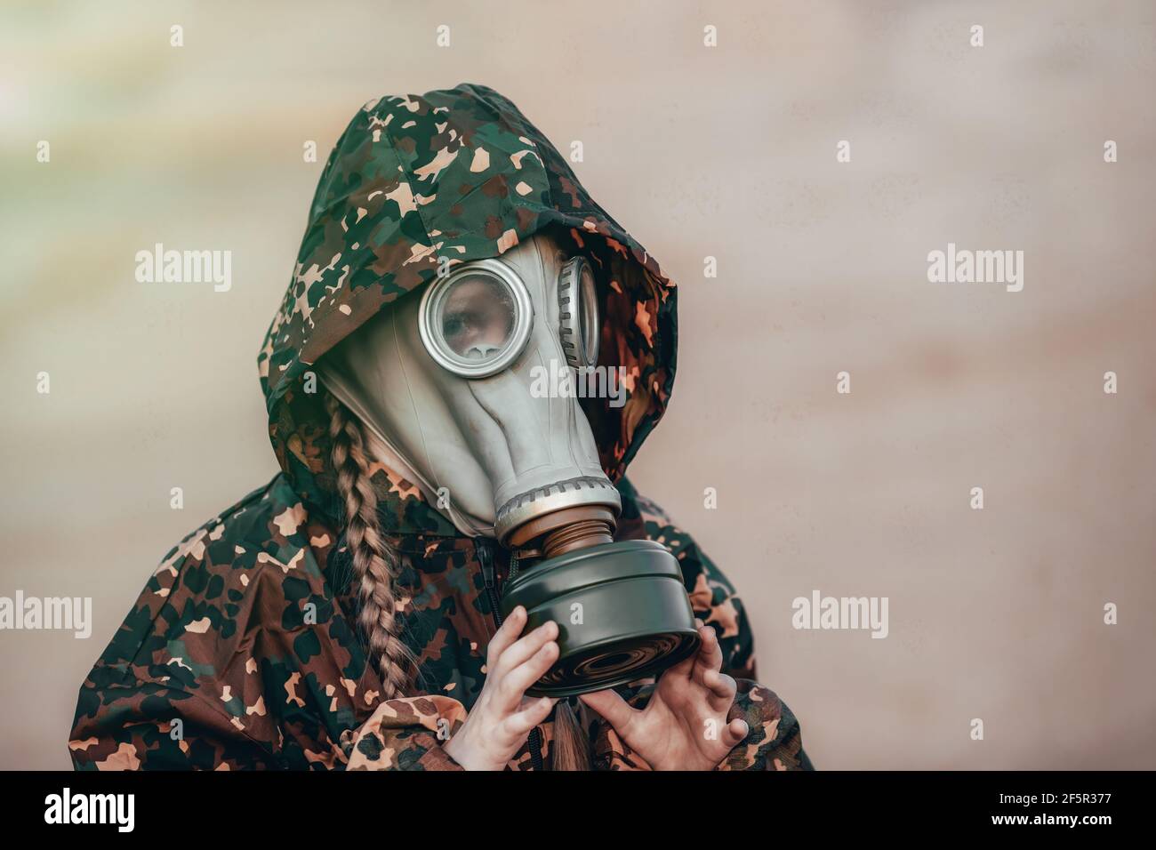 Little kid girl in gas mask in sand desert after apocalypse. Lonely child in respirator. Eco concept about pollution and toxic air. Stock Photo