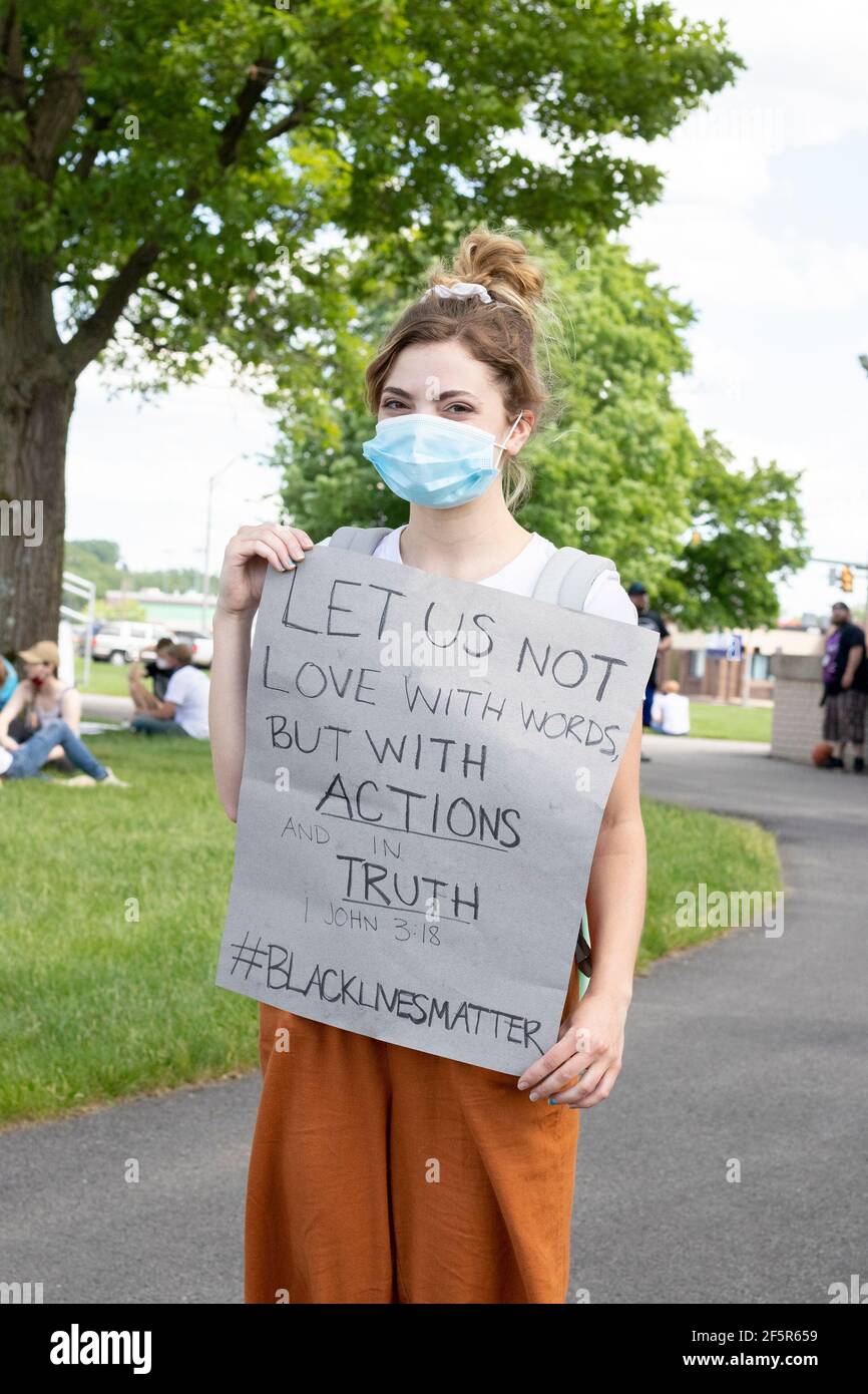 Young White woman with Bible Verse poster at Park wearing a mask Stock Photo