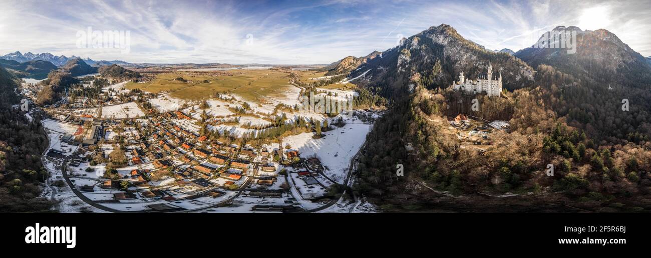 360 Aerial panorama drone shot of picturesque Neuschwanstein Castle on snowy hill in winter sunlight in Germany Stock Photo
